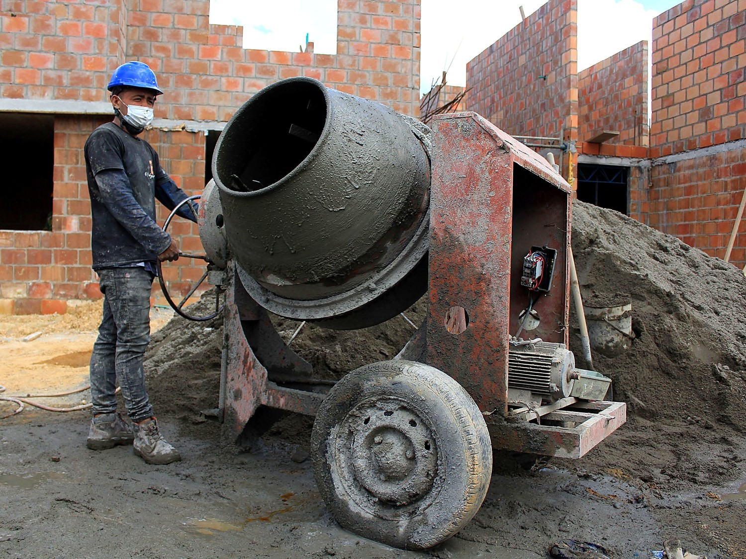 Operário trabalhando ao lado da betoneira na obra